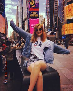 a woman sitting on top of a bench in the middle of a city