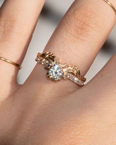 a woman's hand with two gold rings on it and one diamond in the middle