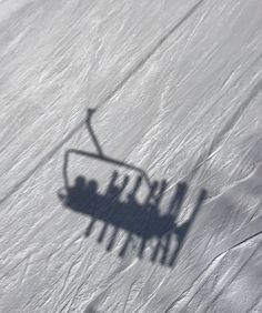 the shadow of a ski lift with people on it's side in the snow