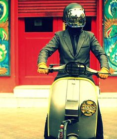 a man in a suit and helmet on a scooter