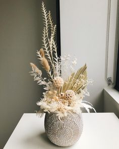 a white vase filled with lots of different types of flowers