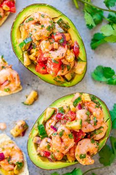 avocados filled with shrimp and salsa on a table next to cilantro