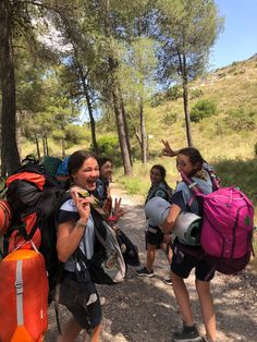 a group of people with backpacks walking on a trail in the woods and pointing at something