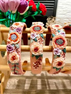 three bracelets with flowers on them sitting in front of a flower potted plant