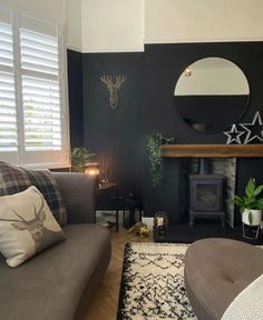 a living room with black walls and white trim on the fireplace, couches and rugs