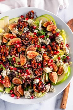 a salad with figs, cheese and nuts in a white bowl on a marble table