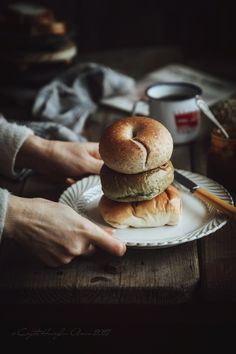 a person holding a plate with two sandwiches on it