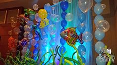 balloons and streamers are hanging from the ceiling in front of an aquarium themed backdrop