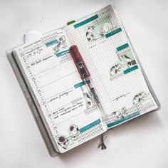 an open planner with skulls on it and a red pen in the middle next to it