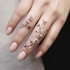 a woman's hand with tattoos on it and flowers painted on the ring finger