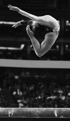 a woman jumping in the air on top of a trampoline at a sporting event