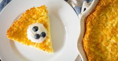 a piece of pie with blueberries and cream on it next to a white plate