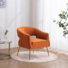 an orange chair sitting on top of a white rug next to a table with a plant