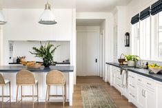 a kitchen with white cabinets and blue counter tops, along with two bar stools