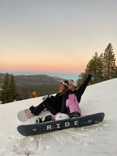 a snowboarder is laying on the ground with her board in front of her