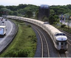 a train traveling down tracks next to a lush green forest