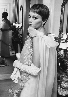 a woman standing in front of a mirror wearing a dress with sheer sleeves and flowers on it