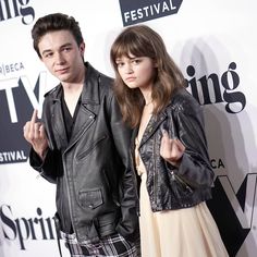 two people standing next to each other on a red carpet