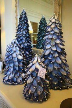 three blue christmas trees sitting on top of a counter next to a mirror in a room