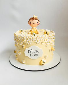 a yellow cake with white flowers and a baby on top