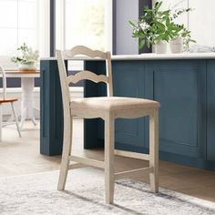 a kitchen with blue cabinets and white counter tops, along with a wooden bar stool