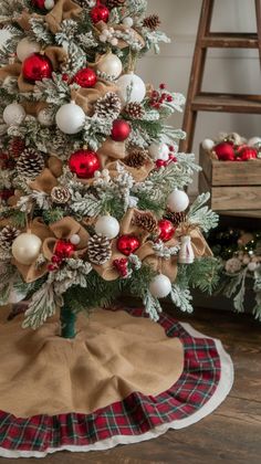 a small christmas tree with red and white ornaments on it, sitting in front of a ladder