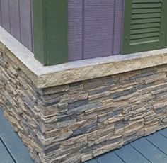 a stone wall with green shutters and purple shutters on the side of it