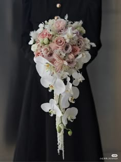 a woman in a black dress holding a bouquet of white and pink flowers on her arm