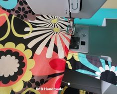 the sewing machine is next to the colorful flowered fabric that has been sewn