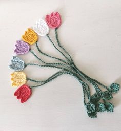 several crocheted flowers are arranged on a white surface with green stems in the center