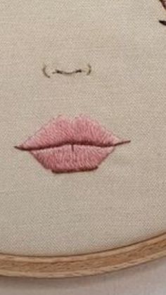 a close up of a embroidery on a piece of cloth with pink lips and eyebrows