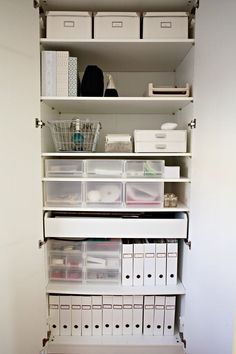 an organized closet with white shelving and lots of storage bins on the bottom shelf