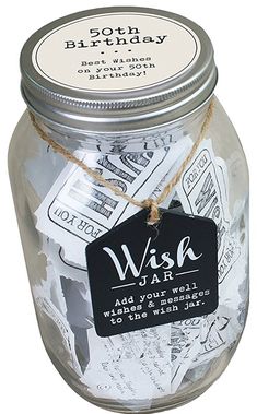 a glass jar filled with money sitting on top of a white table next to a black tag