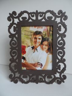 an ornate photo frame with a man and woman holding each other in front of a white wall