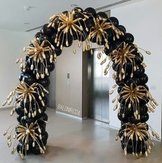 an arch made out of black balloons with gold decorations