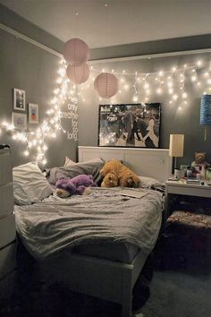 a bedroom with lights strung from the ceiling and stuffed animals on the bed in front of it