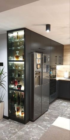 a kitchen area with a refrigerator, sink and potted plant in the corner on the floor