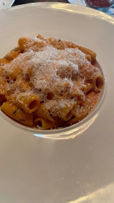 a white plate topped with pasta covered in parmesan cheese