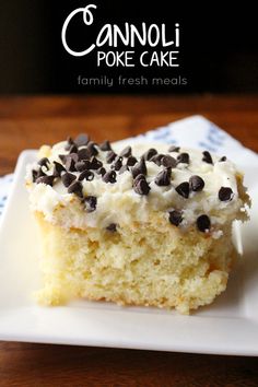 a white plate topped with a piece of cake covered in frosting and chocolate chips