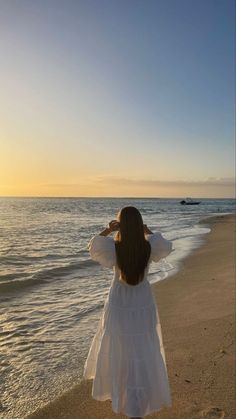 a woman standing on top of a beach next to the ocean