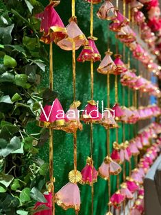 pink and gold bells hanging from a green wall