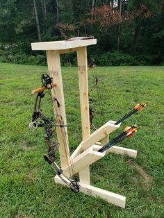 a wooden stand with many different types of bow and arrows on it in the grass