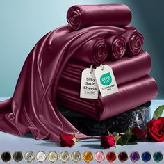 a pile of shiny satin sheets with price tags on them next to red roses and other items