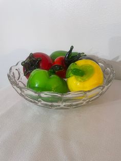 a glass bowl filled with assorted fruit on top of a white cloth covered table