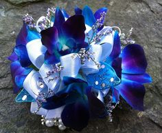 a bridal bouquet with purple and blue flowers on top of a stone surface,