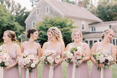 a group of women standing next to each other in front of a house holding bouquets