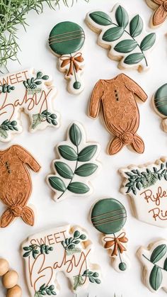 decorated cookies are arranged on a white surface with greenery and baby's breath