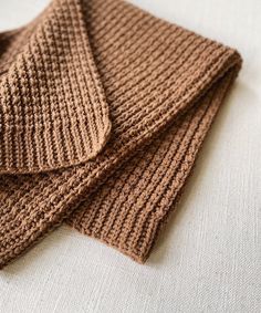 two brown knitted scarves laying on top of each other