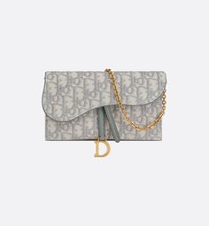 The Saddle pouch with chain, crafted in gray Dior Oblique jacquard, is a hybrid creation with a both modern and streamlined design. The accessory has an asymmetrical flap featuring an antique gold-finish metal D stirrup. Thanks to its detachable chain strap, the small pouch may be worn over the shoulder, crossbody or carried by hand.. Gris Dior, Tas Lv, Dior Purse, Wallet With Chain, Dior Oblique, Christian Dior Couture, Dior Wallet, Fancy Bags, Best Wallet