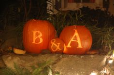 three carved pumpkins with the letters b and a on them sitting in front of a house